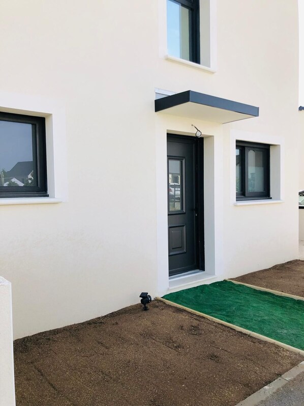 A modern building with a flat facade, a black door, and a small window.