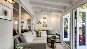Un salón acogedor con un sofá gris, una mesita auxiliar y un ventanal grande.