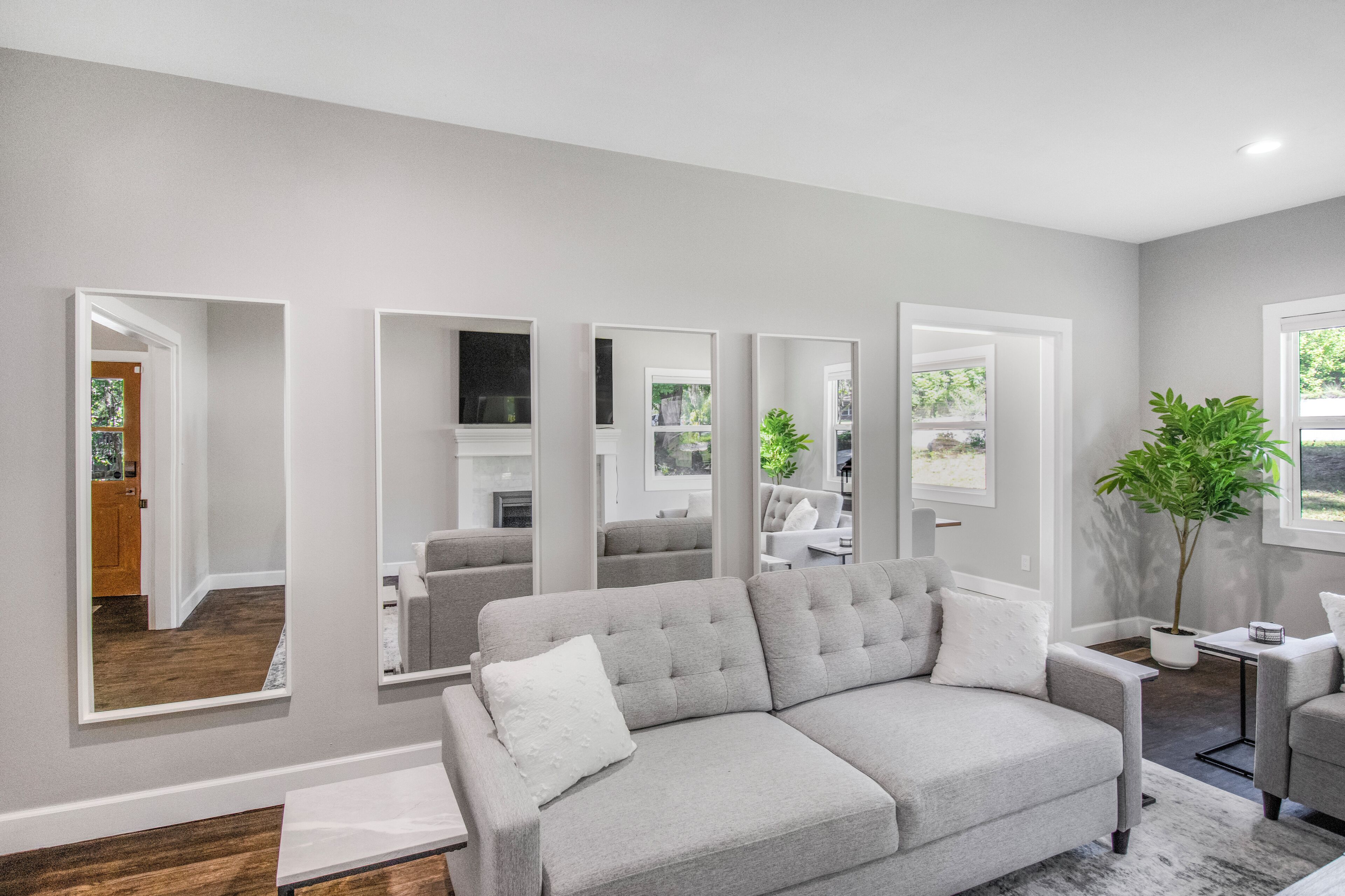 A modern living room with a grey sofa, a small side table, and a potted plant.