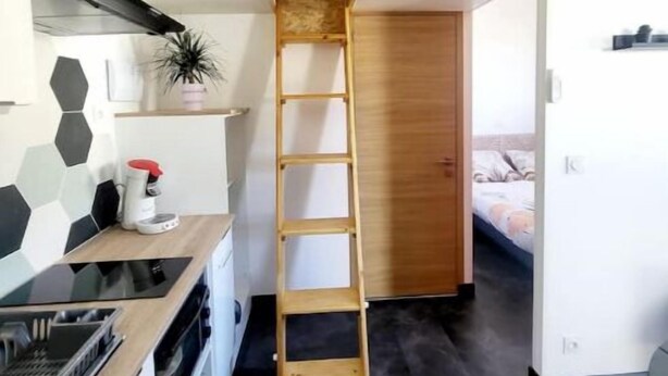 A compact kitchen with a wooden ladder leading to a loft bedroom. - House sleeps 4 (Saint-Léger-sous-Brienne)