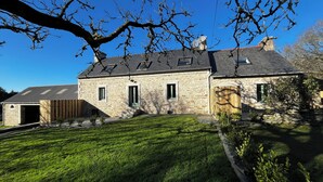 A stone house with a sloped roof, a covered garage, and a well-maintained lawn.