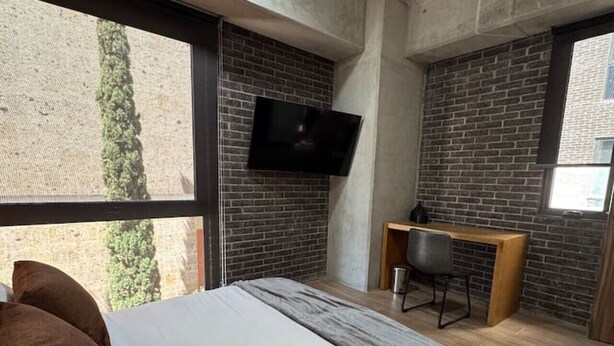 Une chambre moderne avec un grand lit, un bureau, une télévision et une vue sur l’extérieur.