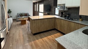 Une cuisine moderne avec un îlot central en bois, un four encastré et une grande fenêtre.