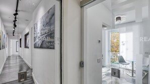 A modern hotel corridor with a glass door leading to a dining area, a black and white photograph on the wall, and a clean, minimalist design. - Gallery Suite (Civitavecchia)
