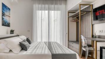 Un dormitorio moderno con una cama, un escritorio, una silla y un televisor mostrando el logotipo de Netflix.