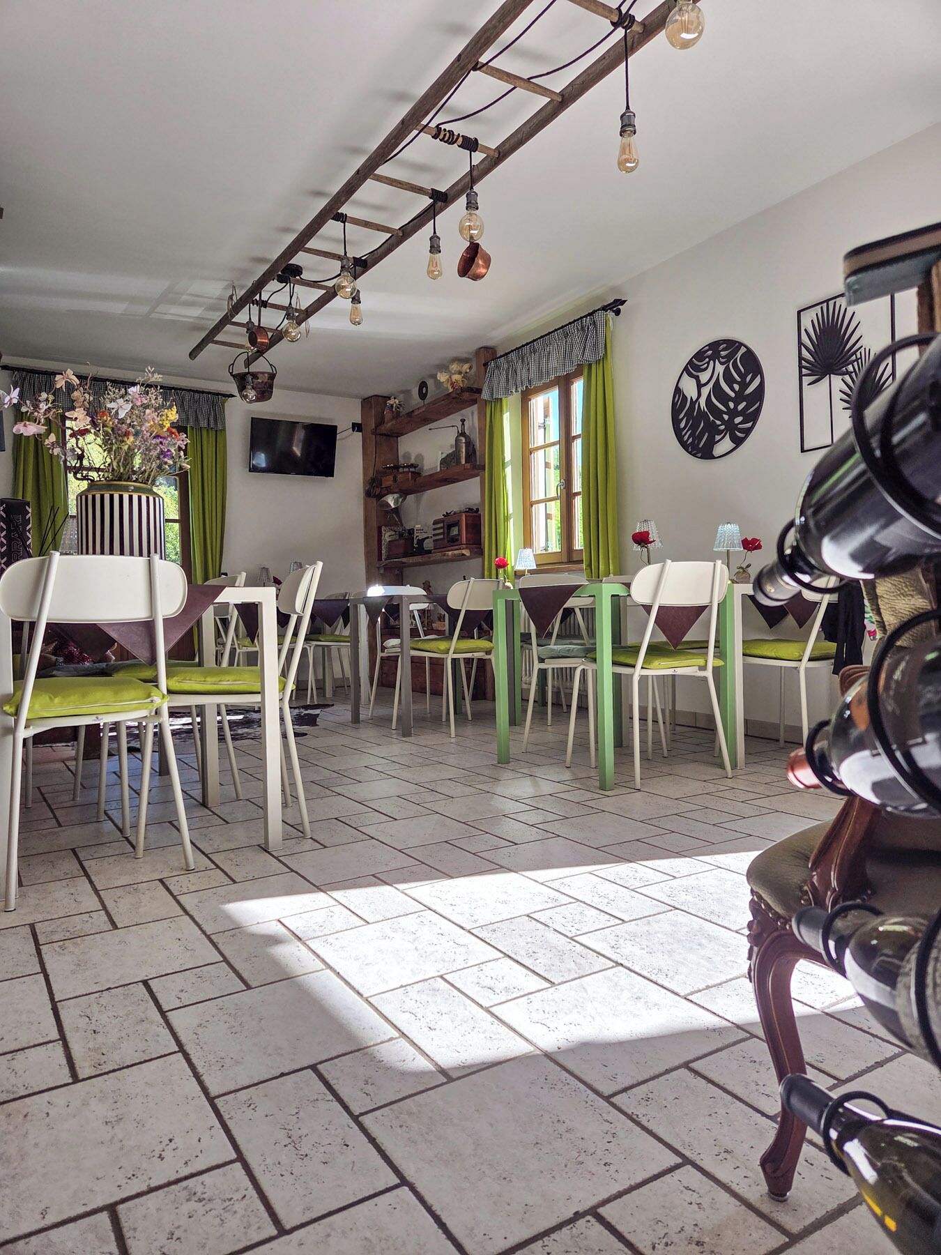 Een eetgedeelte met meerdere stoelen en tafels, een houten plafond met hangende lampen en een raam met gordijnen.