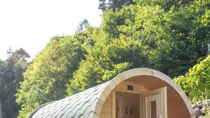 A cylindrical wooden structure with a door, surrounded by rocks and greenery. - AGRITURISMO VALFRAJA (Cembra)