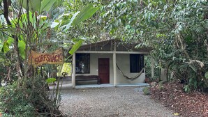 Un petit bâtiment d’un seul étage, doté d’un porche et d’un hamac, entouré d’une végétation luxuriante.