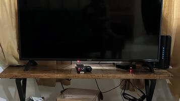 En tv-apparat står på ett träställ. En fjärrkontroll ligger framför den, och under tv:n finns en låda med texten ”Touchstone Telephony Gateway”.