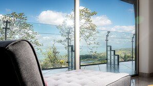 Une chambre moderne dotée d’une grande fenêtre offrant une vue panoramique sur un lac et des montagnes.
