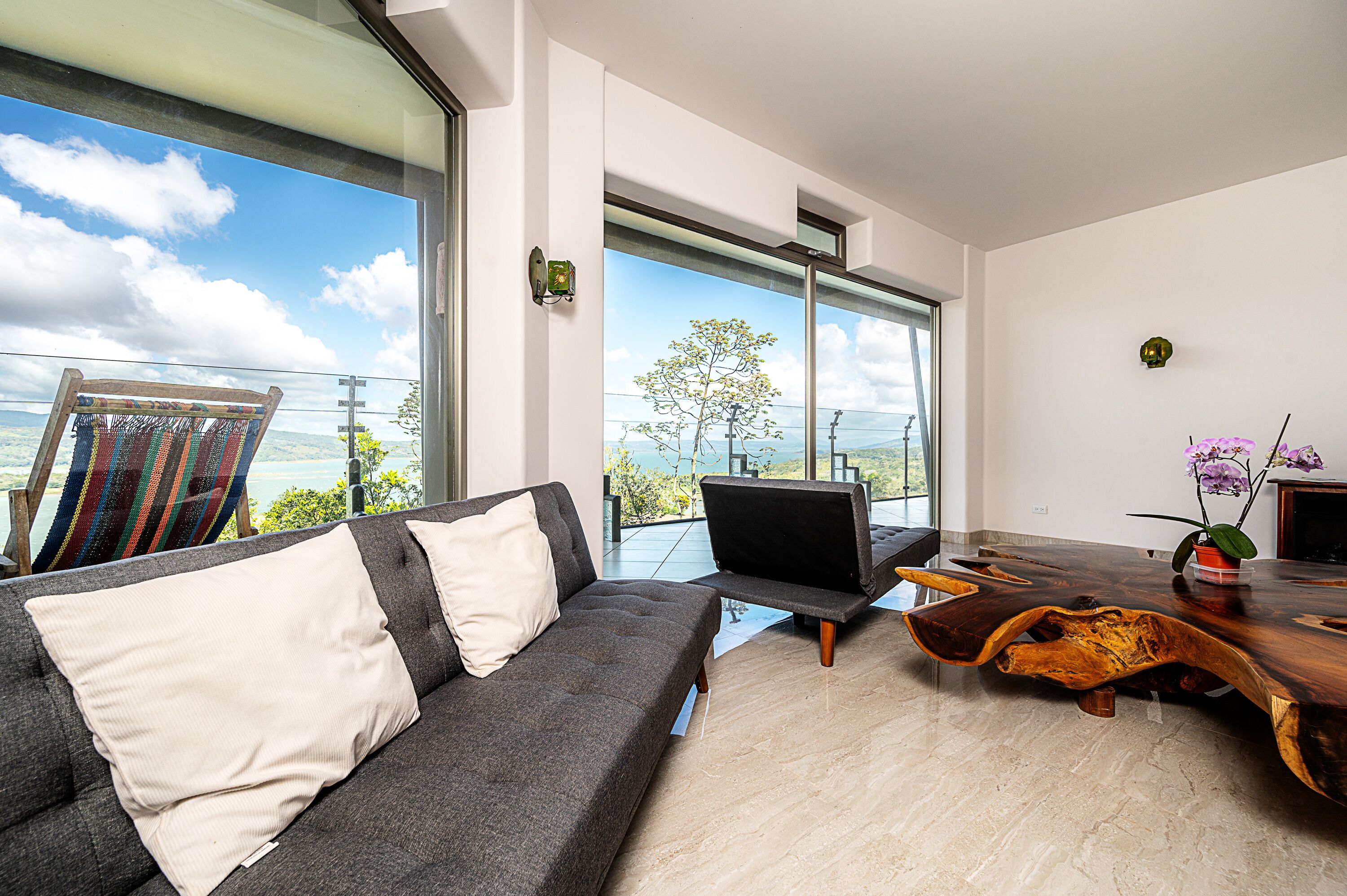 A modern living room with a sofa, a wooden coffee table, and a view of the outdoors.