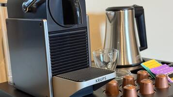 Une machine à café Krups avec une verseuse en verre et une bouilloire posées sur une table.