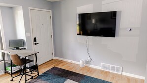 Una habitación con escritorio, silla y televisor de pared.
