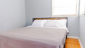 Un dormitorio con cama, ventana y suelo de madera.