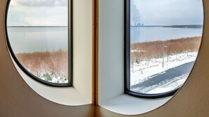 Une pièce dotée de deux fenêtres, chacune offrant une vue sur une étendue d’eau et un paysage enneigé.
