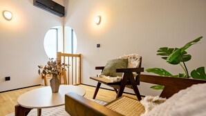 Une pièce chaleureuse avec une table ronde, deux chaises, une grande fenêtre et une plante en pot.