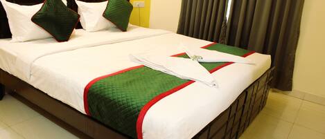A neatly made bed with white and green bedding, a brown headboard, and a power outlet on the wall.