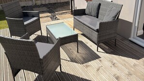 An outdoor patio with wicker furniture, a glass table, and a wooden deck. - Spacious, entire 3 bedroom house in Wool (The Purbecks) (Wool)