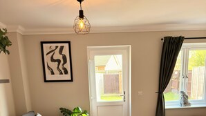 A modern living room with a grey sofa, a wooden coffee table, and a door leading to a garden. - Spacious, entire 3 bedroom house in Wool (The Purbecks) (Wool)