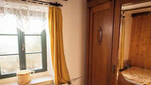 Ein Zimmer mit einem Holzschrank, einem Fenster mit gelbem Vorhang und einer Heizung.