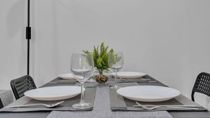Een eettafel gedekt met witte borden, glazen en een klein sierplantje.