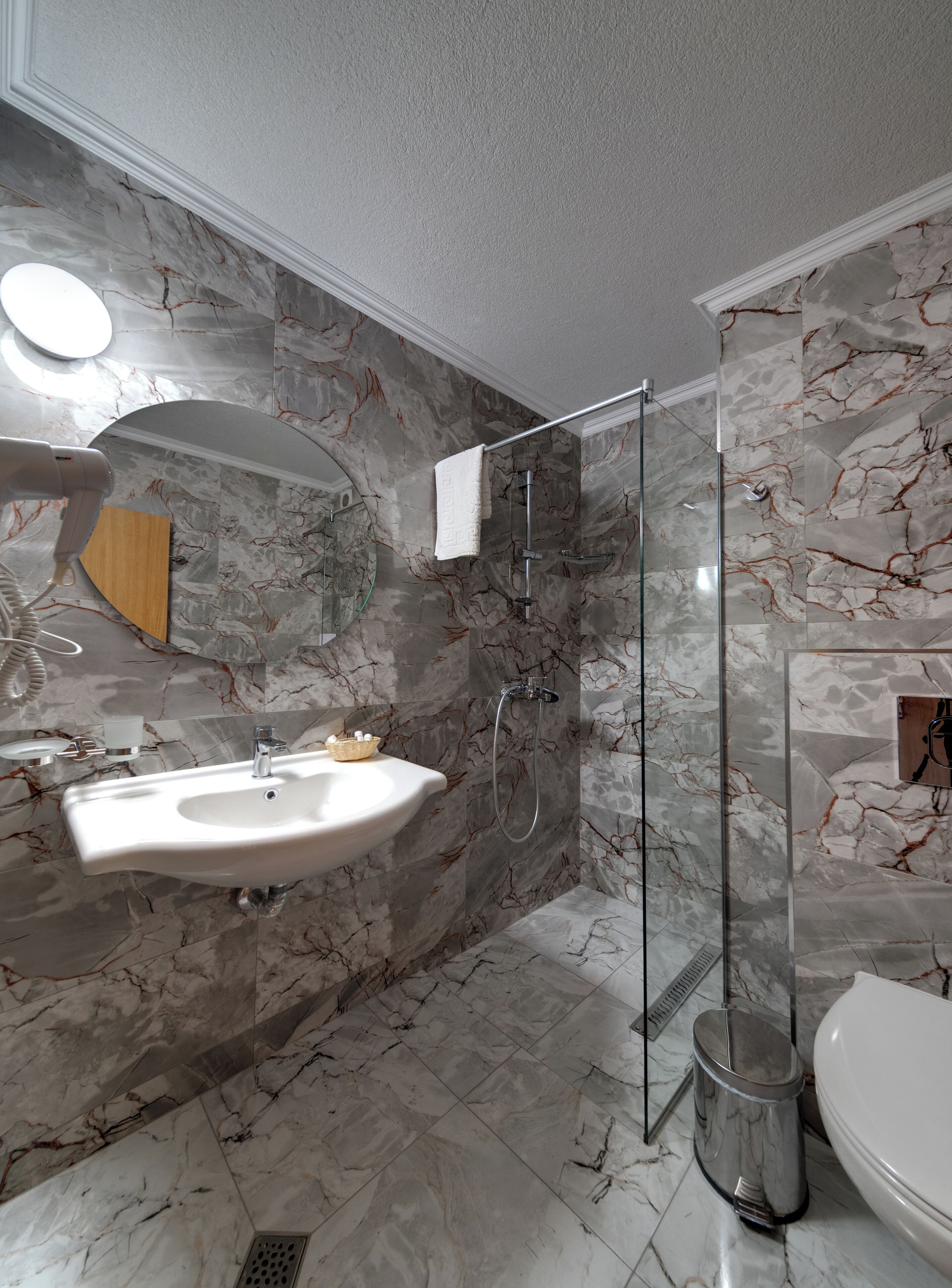 A bathroom with a marble sink, a glass shower enclosure, and a toilet.