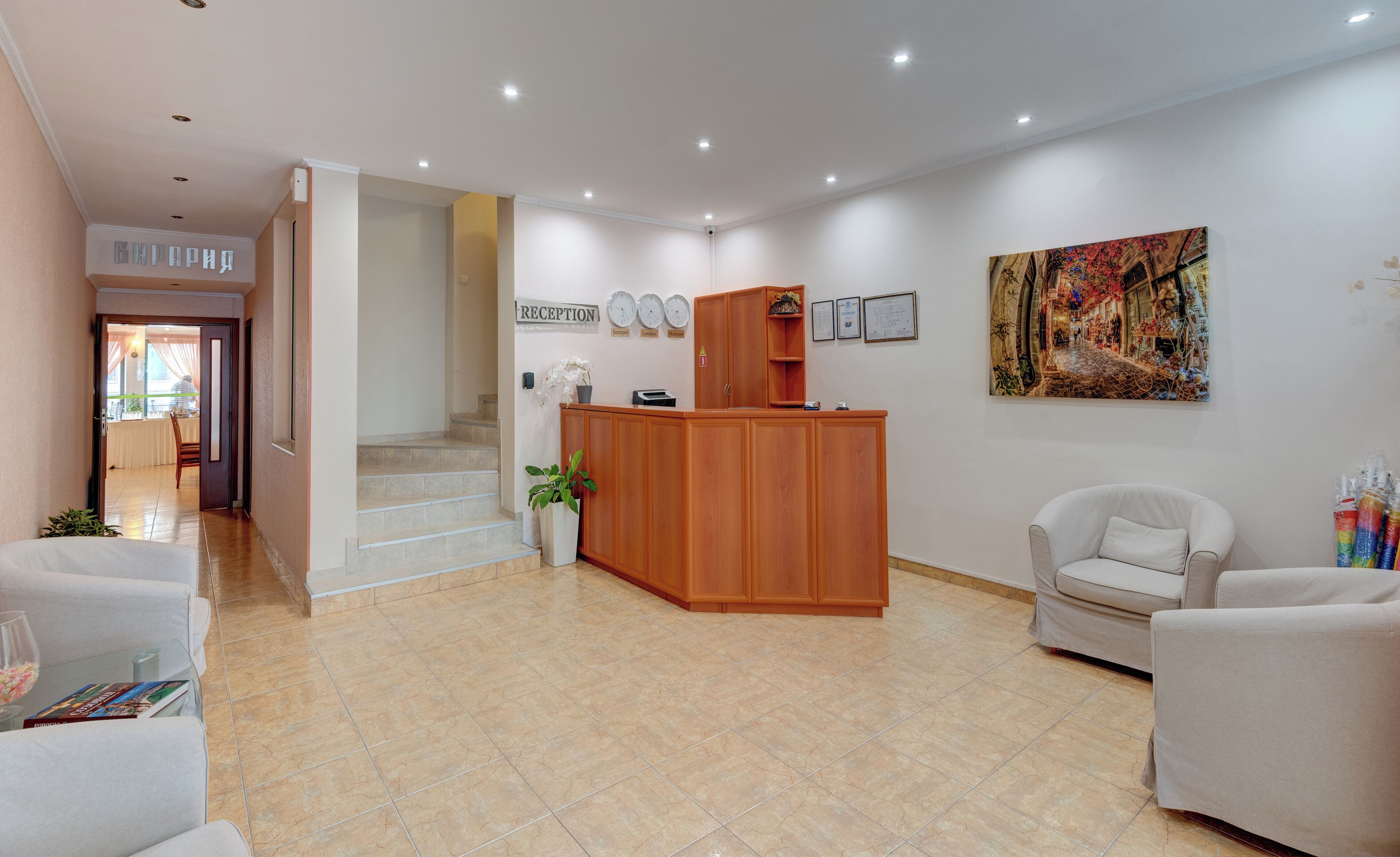 Un espace d’accueil avec un comptoir de réception en bois, une enseigne indiquant « accueil », une horloge et un tableau accroché au mur.