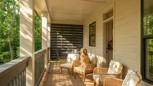 Eine überdachte Veranda mit Korbmöbeln und einem Hund.