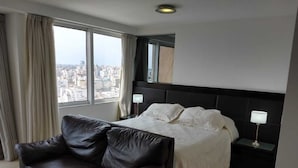 A modern hotel room with a large bed, a leather sofa, and a city view through the window. - EXTRAORDINARY LOFT in Cordoba 22C (Córdoba)