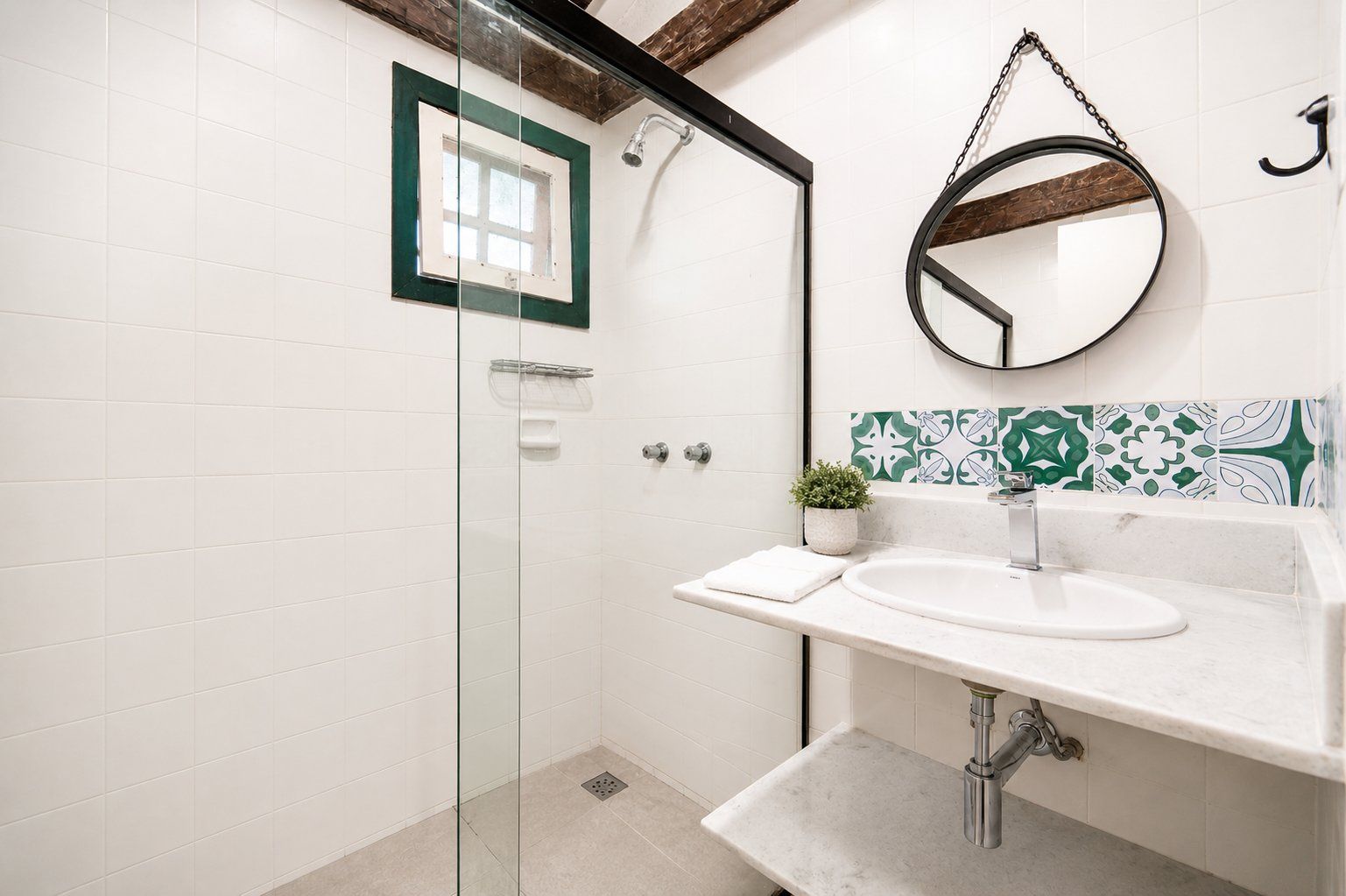 A modern bathroom with a glass shower enclosure, a white sink with a marble countertop, and a decorative mirror.