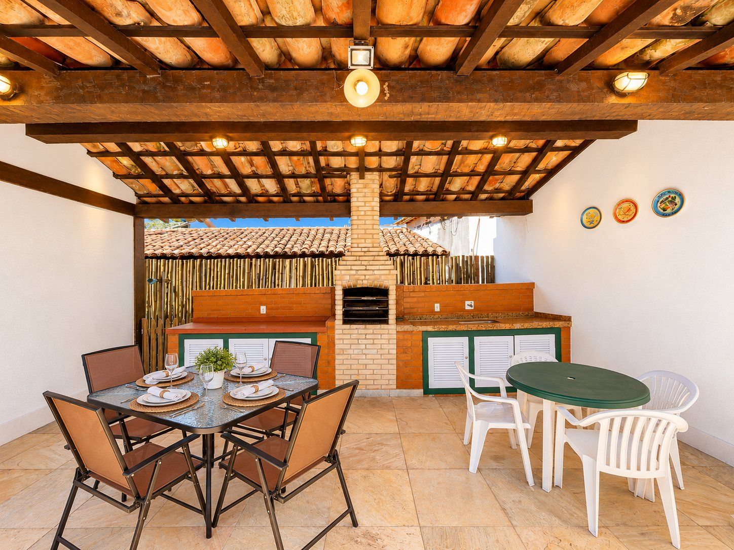 An outdoor patio with a brick oven, a dining table set with plates and glasses, and a seating area with chairs.