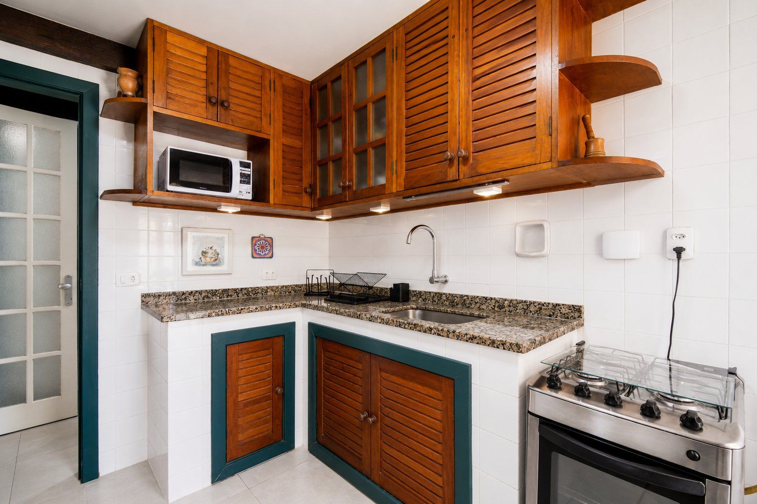 Une cuisine avec des meubles de rangement en bois, un four à micro-ondes, un évier et une cuisinière.