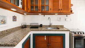Una cocina con encimeras de granito, armarios de madera, un lavamanos de acero inoxidable y una estufa.