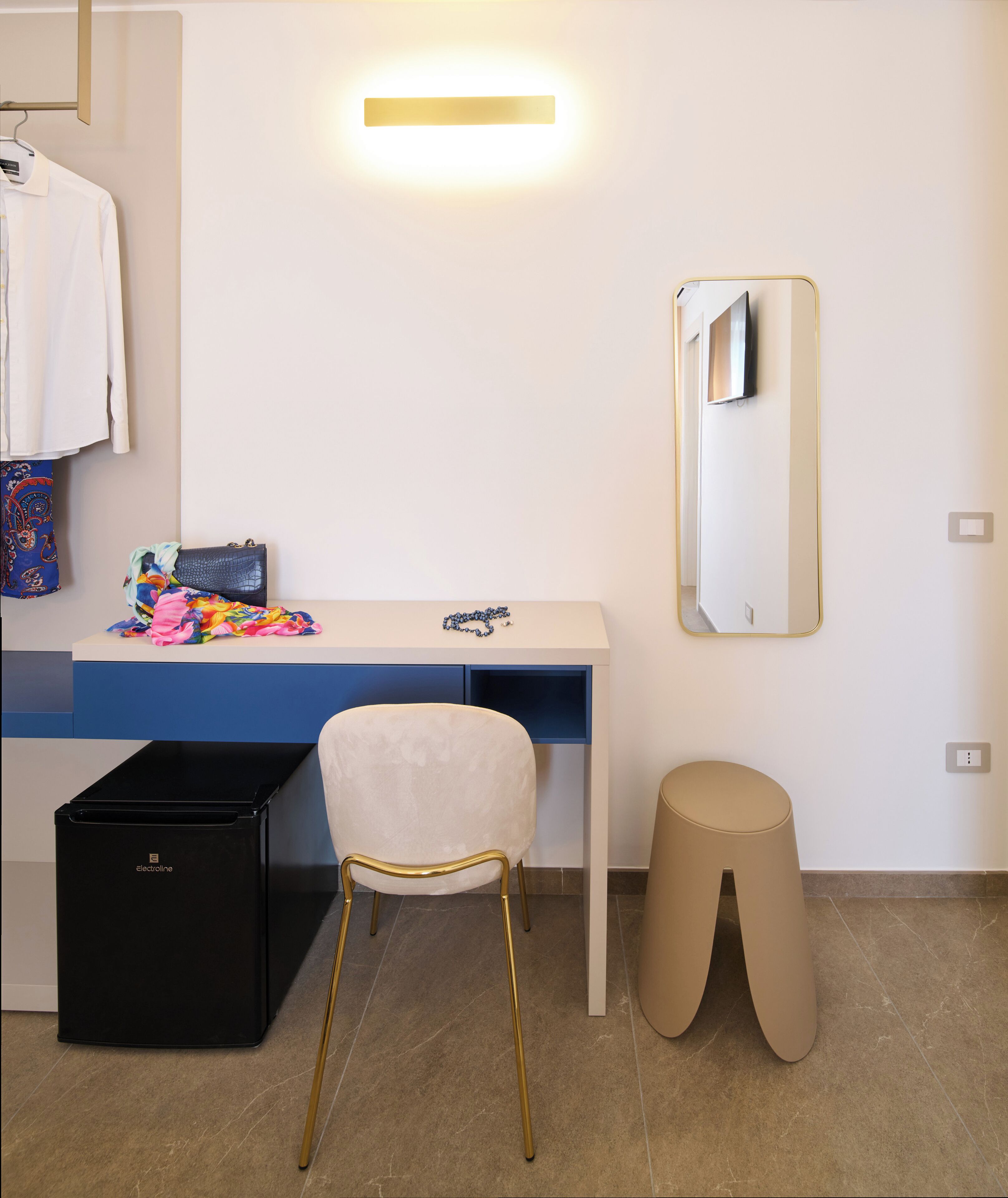 A modern bathroom with a white vanity, a mirror, a chair, and a trash bin.