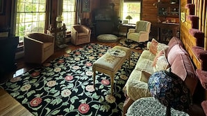 Interior acogedor de una cabaña con paredes de madera, techo alto y ventanas amplias. Hay dos sofás, una mesita y una silla.