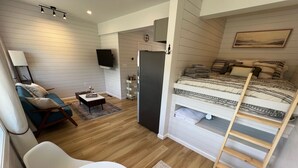 A compact room with a bunk bed, a sofa, a small table, and a TV. - New - The Skyline Flat (Front Royal)