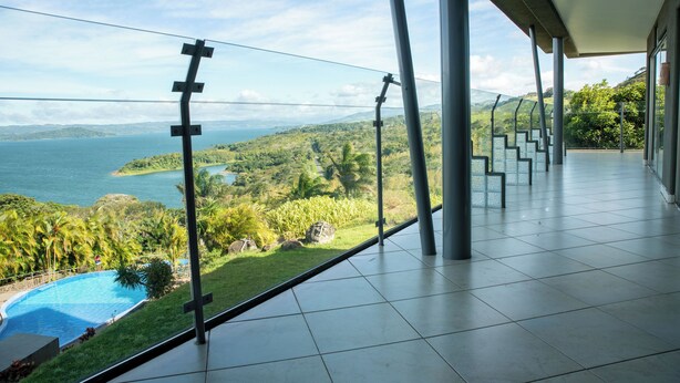 Een moderne hotelkamer met een ruim balkon met uitzicht op een schilderachtig meer en weelderige begroeiing.