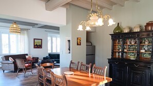 A dining area with a wooden table and chairs, a chandelier, and a cabinet with decorative items.