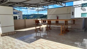 A covered outdoor area with a tiled floor and a wooden table. - Air-conditioned studio, wifi in the center of Piratuba SC (Piratuba)