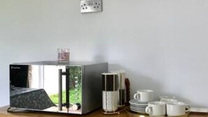 A kitchenette with a coffee maker, a kettle, and a tray with cups. - The Woodfarm Lodge - 3 Bedroom House With Parking (Oxford)