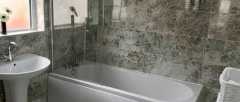 A bathroom with a bathtub, a sink, and a mirror.