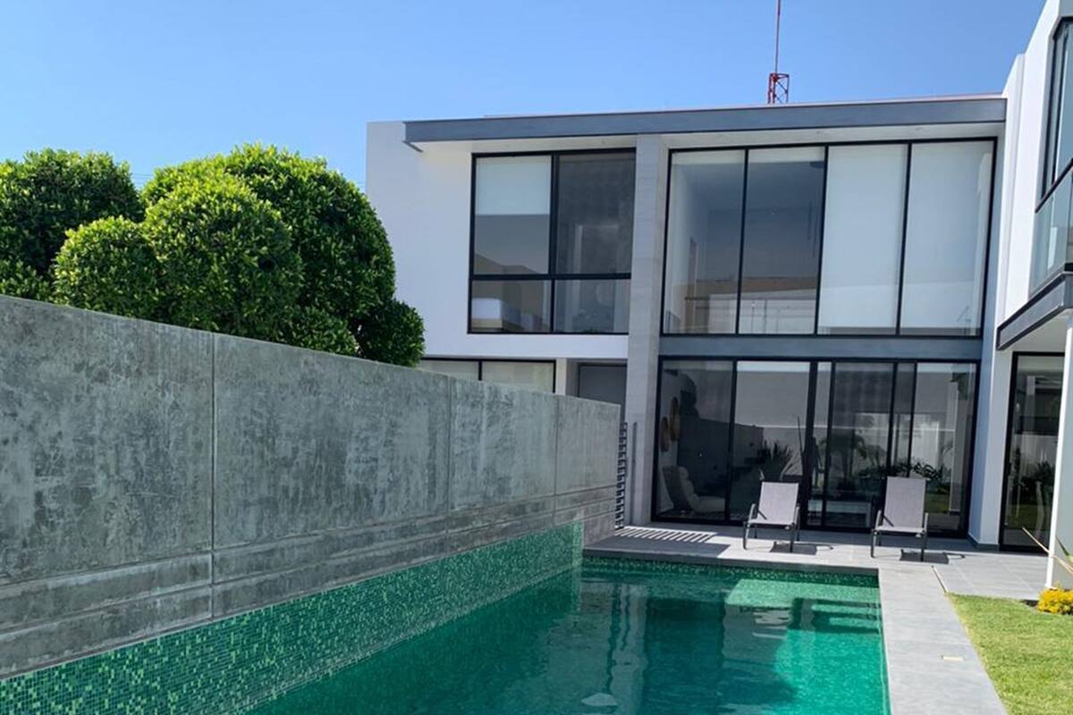 Una casa moderna amb piscina, una paret de formigó i una gran finestra al davant.