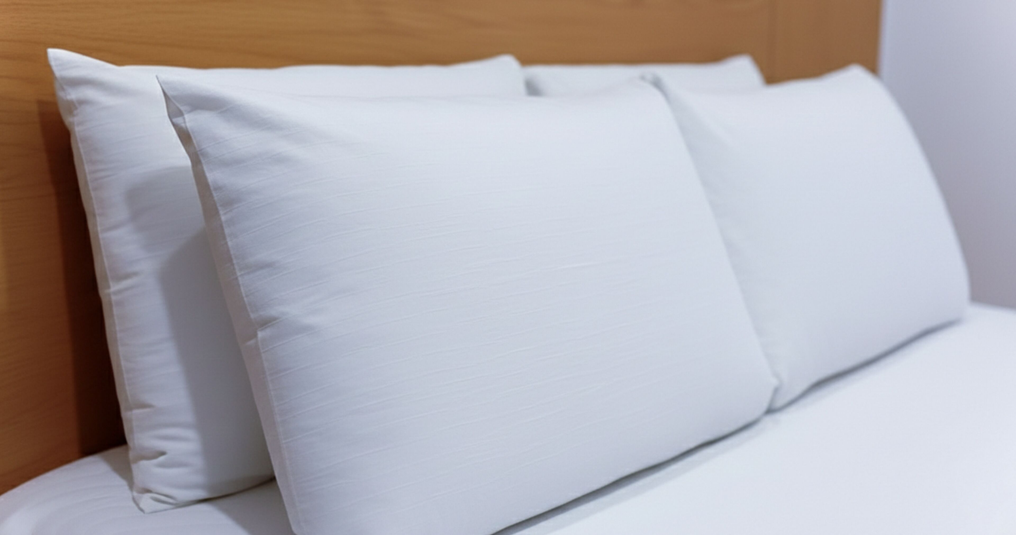 A neatly made bed with white bedding and pillows.