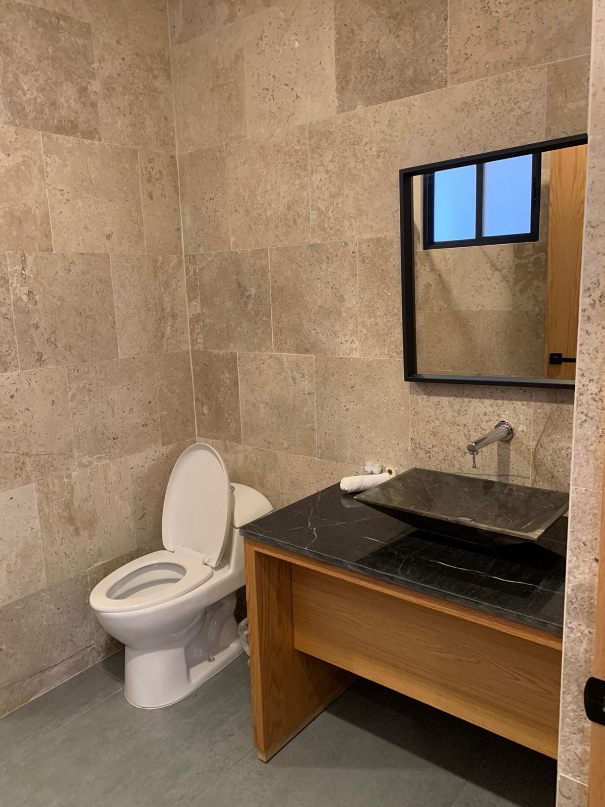 A modern bathroom with a toilet, sink, and mirror.