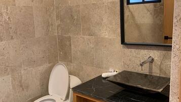 A modern bathroom with a toilet, sink, and mirror.