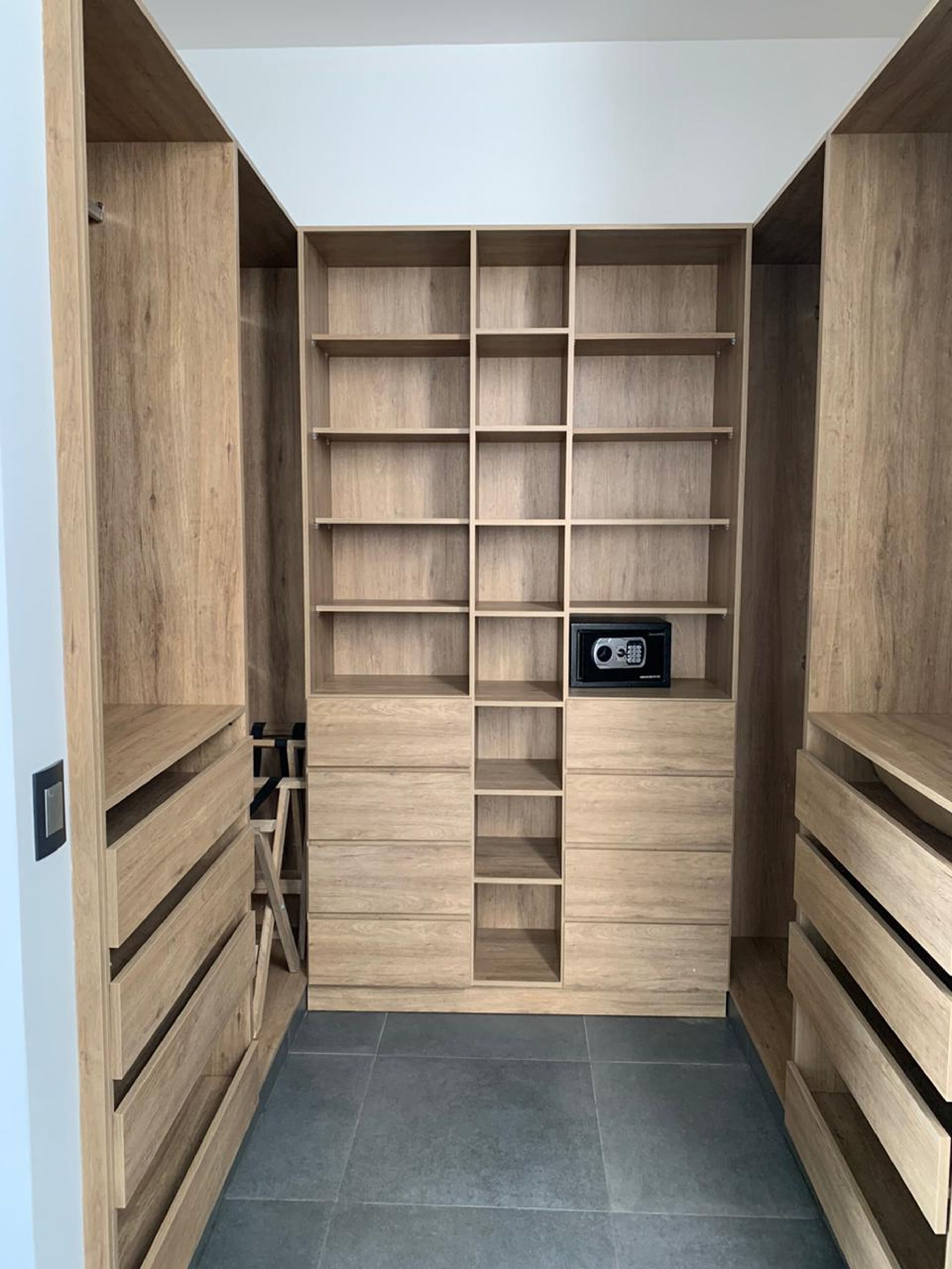 Un armario moderno y minimalista con varias estanterías de madera y un altavoz integrado.