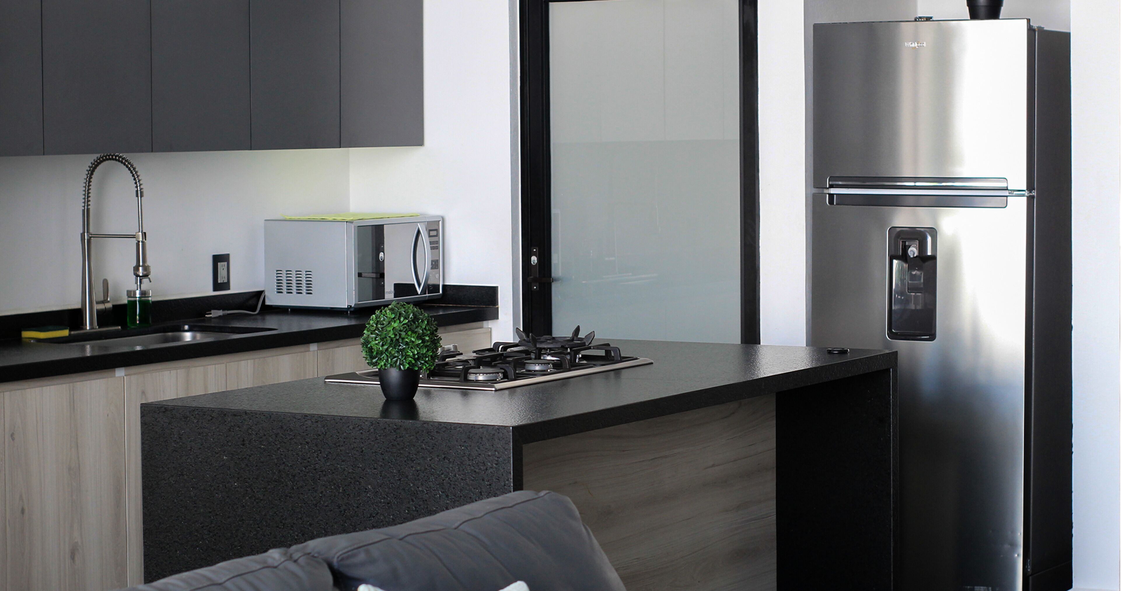 A modern kitchen with a stainless steel refrigerator, a built-in microwave, a gas stove, and a sink with a faucet.