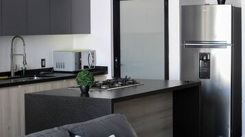 A modern kitchen with a stainless steel refrigerator, a built-in microwave, a gas stove, and a sink with a faucet.