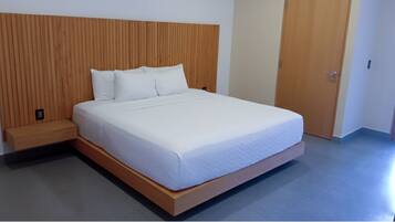 Una cama con cabecera de madera, un banco de madera y una puerta a la derecha.