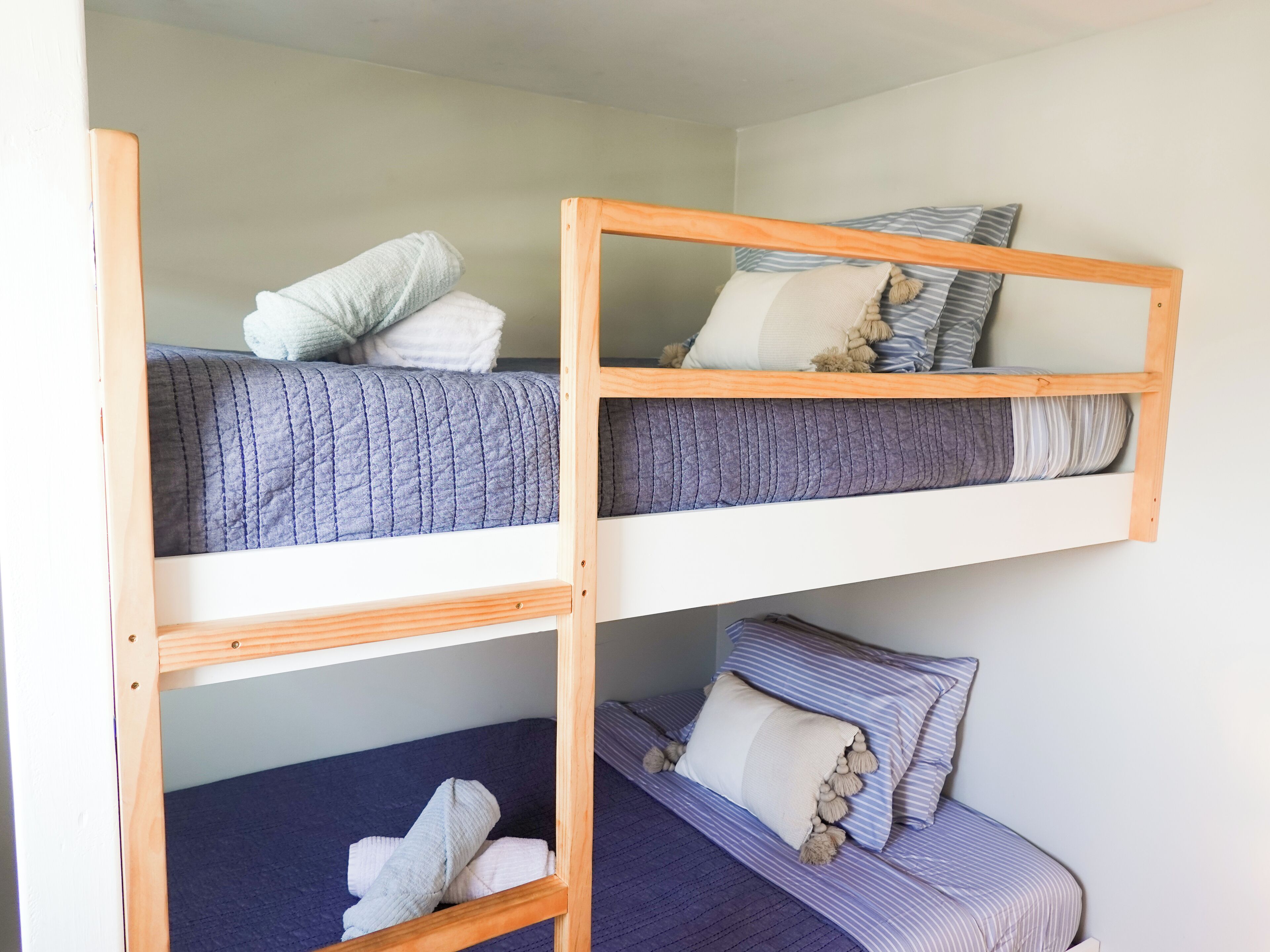 A bunk bed with two levels, each with a pillow and a blanket.